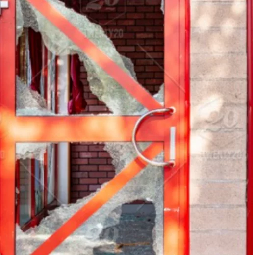 Close-up of a broken glass door with red frame and a shiny metal handle.