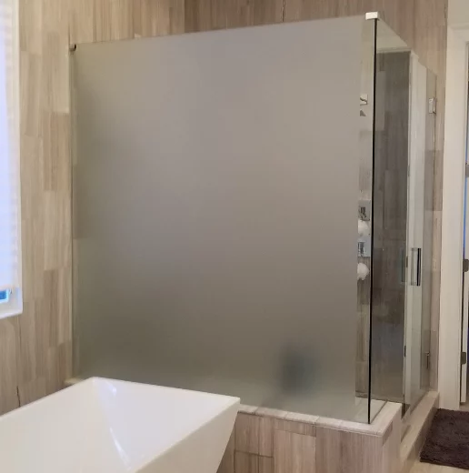 Modern bathroom with a frosted glass shower, wooden walls, and a white freestanding bathtub.