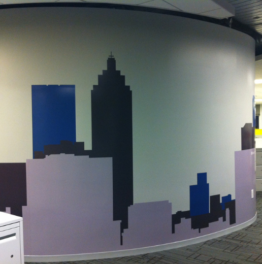 Artistic mural of a city skyline in shades of blue and gray on a curved office wall.