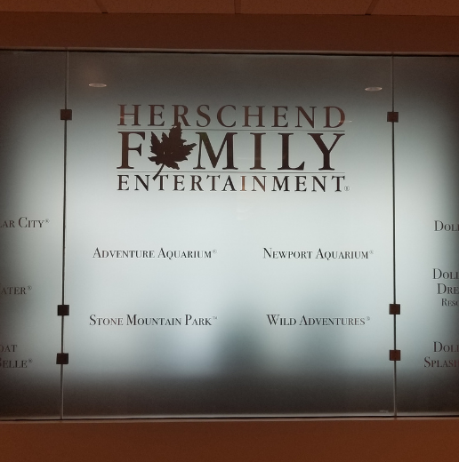 Frosted glass panel with 'Herschend Family Entertainment' logo and list of attractions.