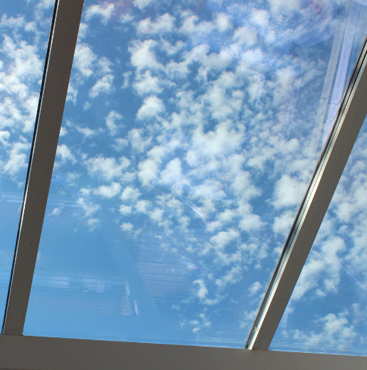 View of a blue sky with scattered clouds through a quadruple-pane window.