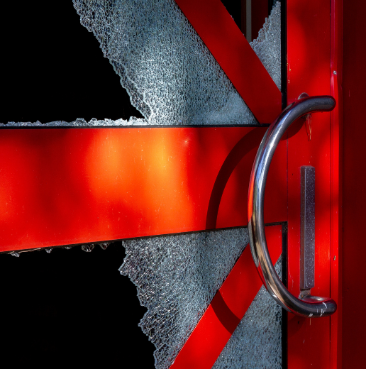 A shattered glass door with a red frame and a silver handle.
